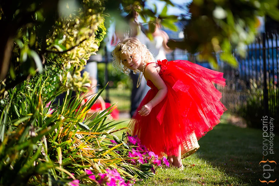 flower girl in red tutu playing in the flowers