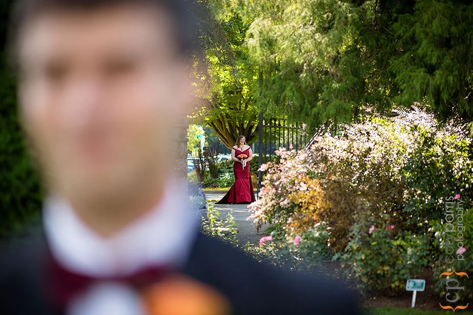 bride in a red dress walking behind groom at woodland park rose garden