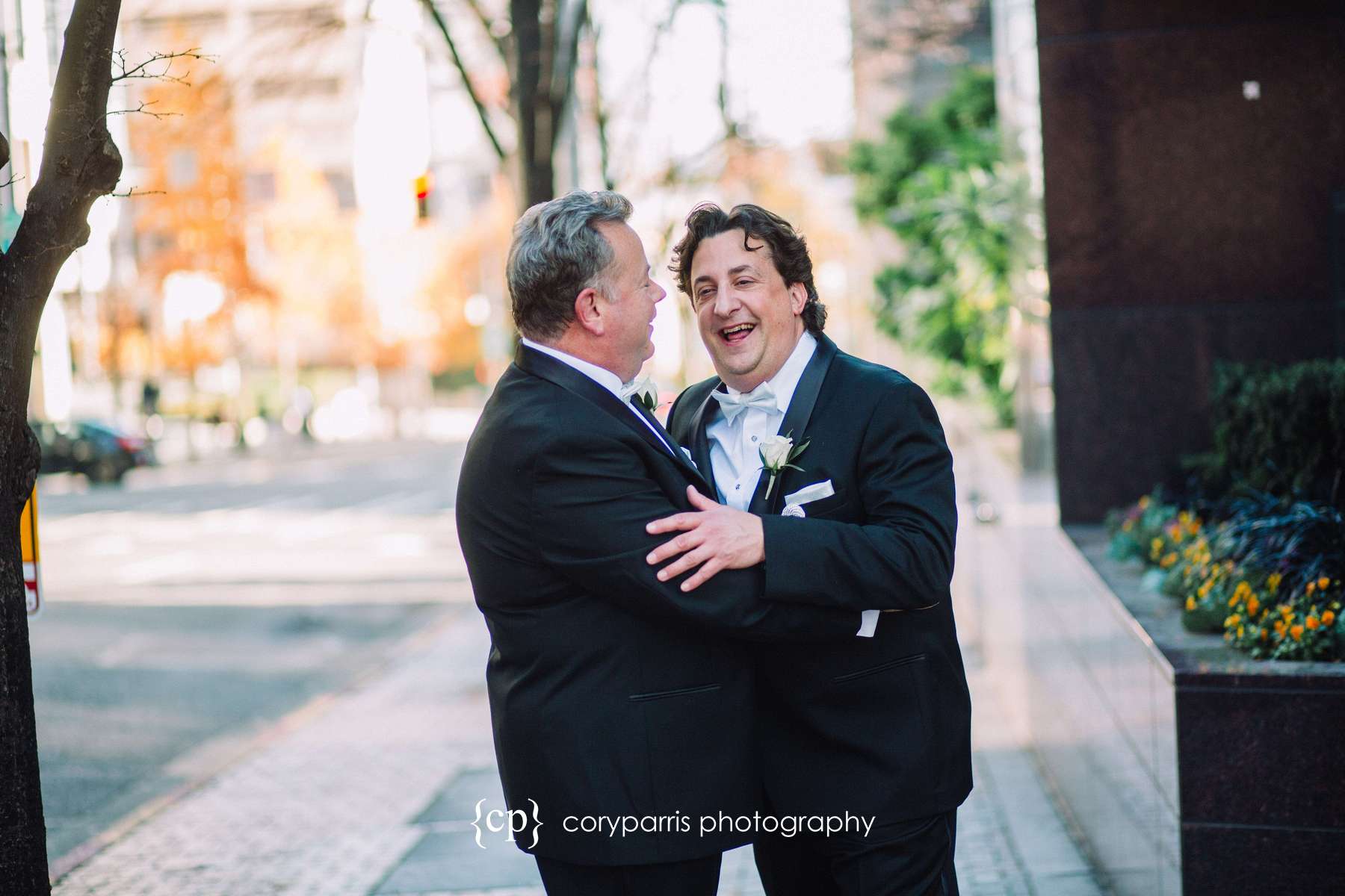 The two grooms laughing together during portraits on the streets of Seattle
