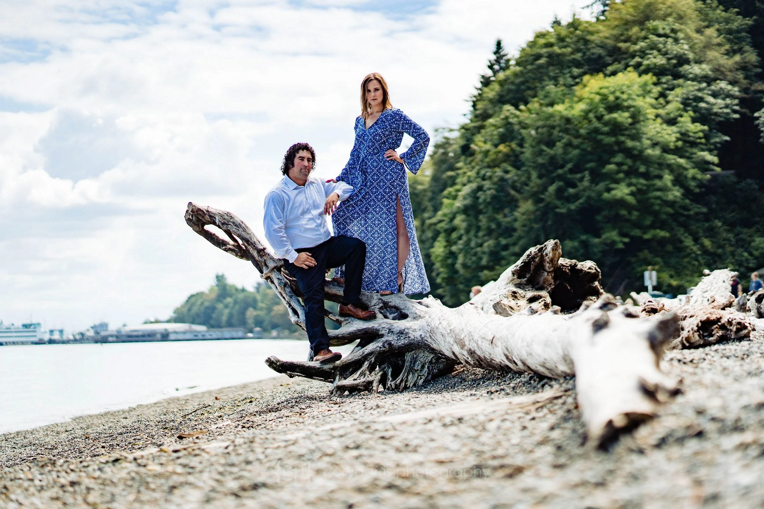 Erin & Adam pose for their engagement portraits on a piece of driftwood at Point Defiance Park in Tacoma.