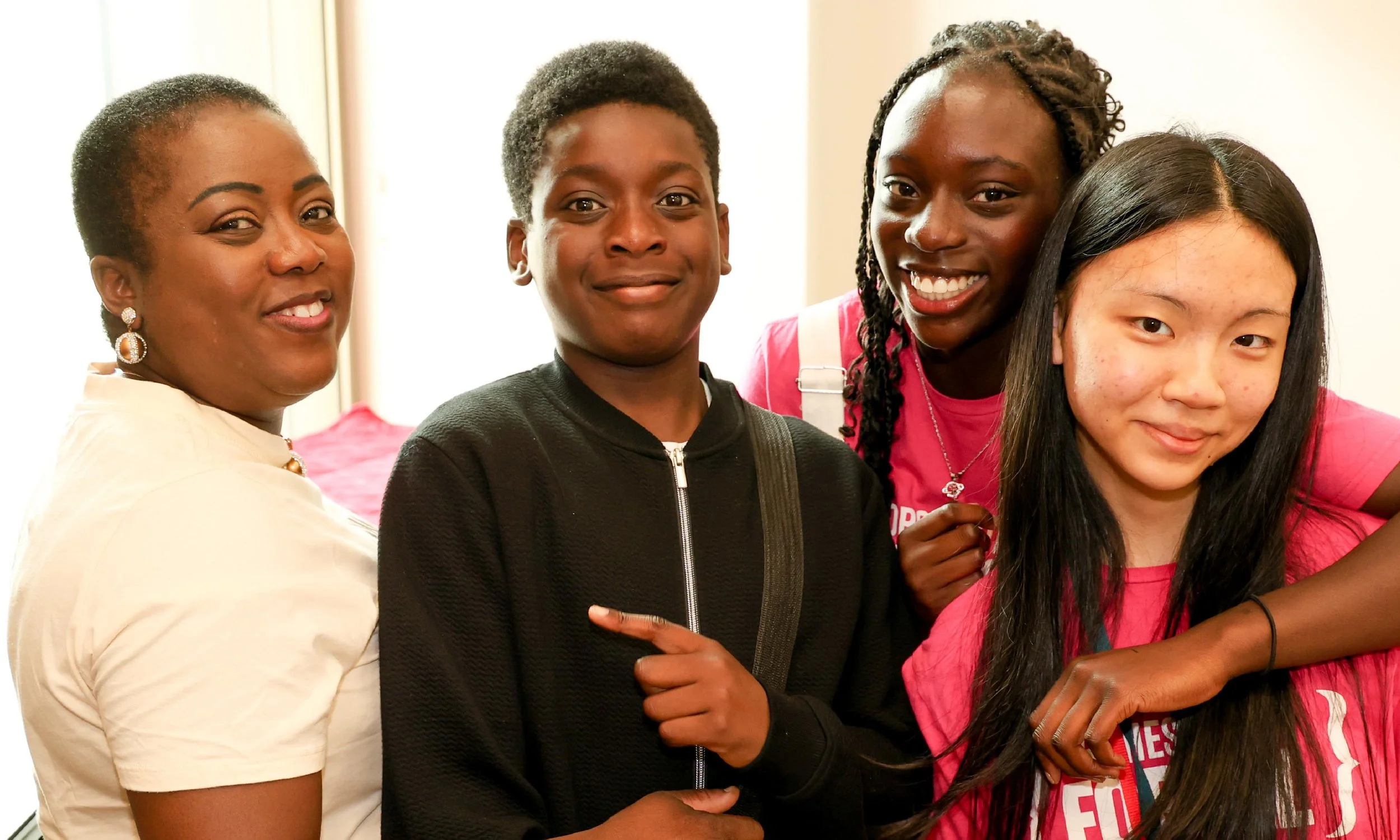 Three NOFA musicians in pink Orchestras for All branded t-shirts and a parent.