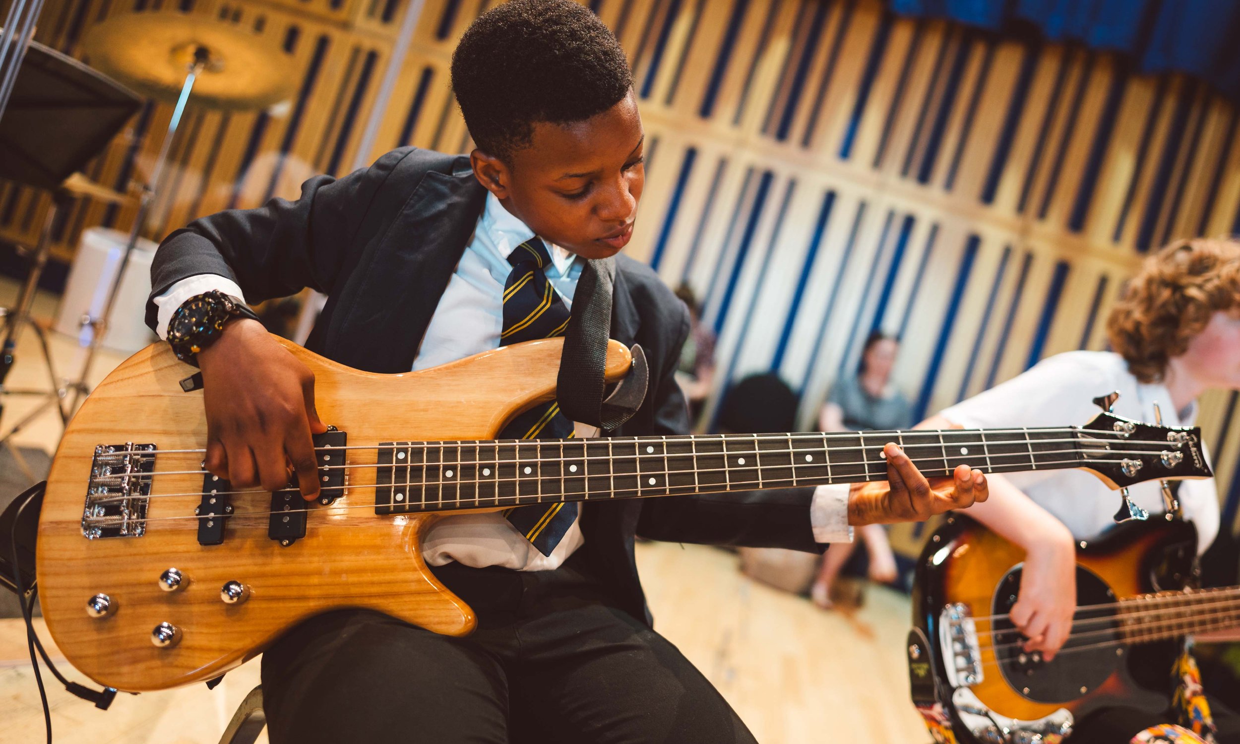 A Modulo student playing the bass guitar during a rehearsal.