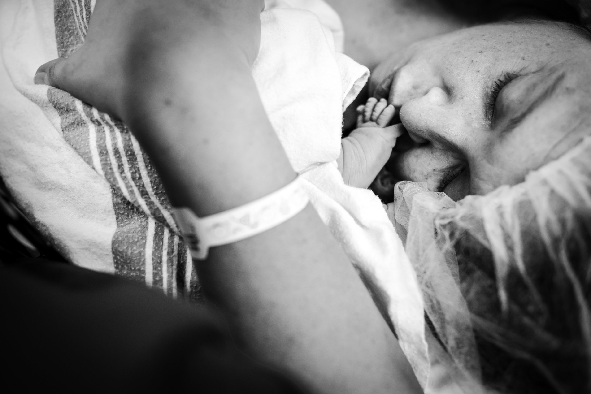 close up of mother kissing newborn foot after gentle cesarean in Fort Worth Texas