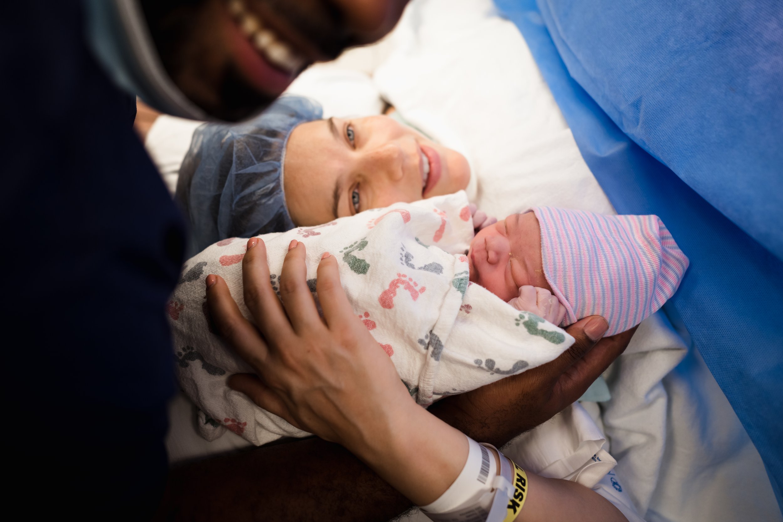 dad holds baby close to mom's face after family-centered cesarean birth in Dallas