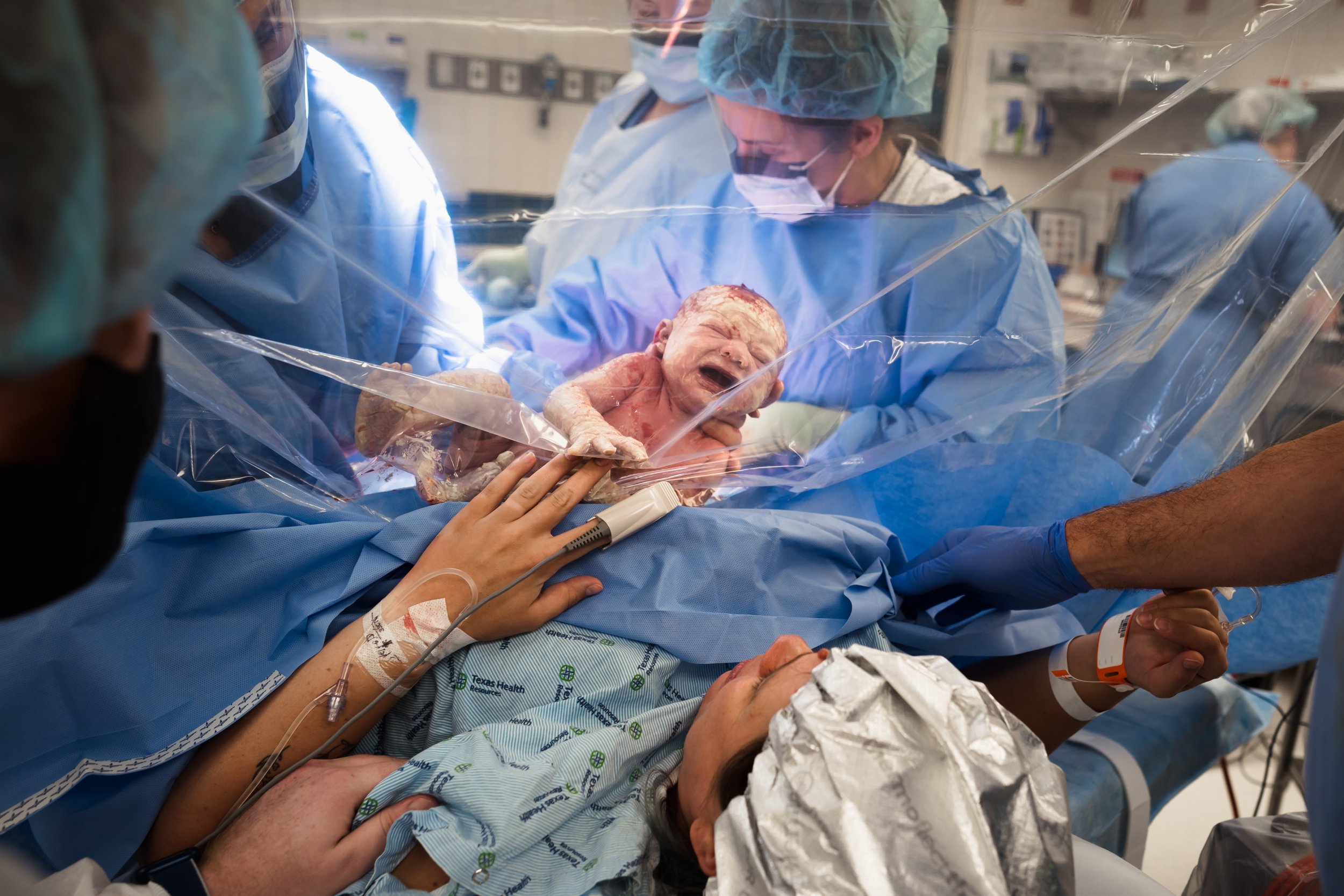 baby is lifted to clear drape during gentle cesarean birth in Frisco, TX