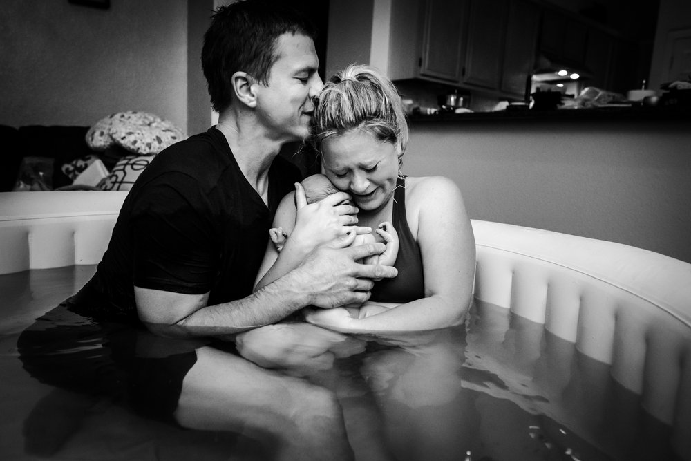 dad kisses wife's forehead after water birth at home