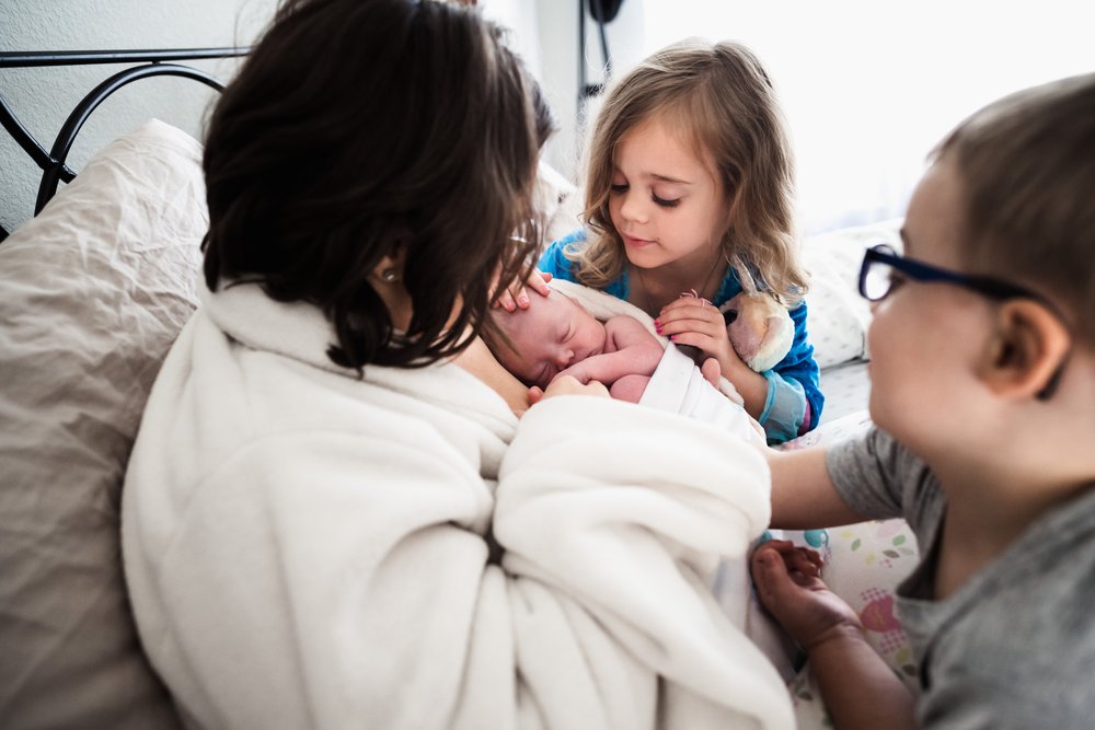 big siblings meet newborn at home with mom 