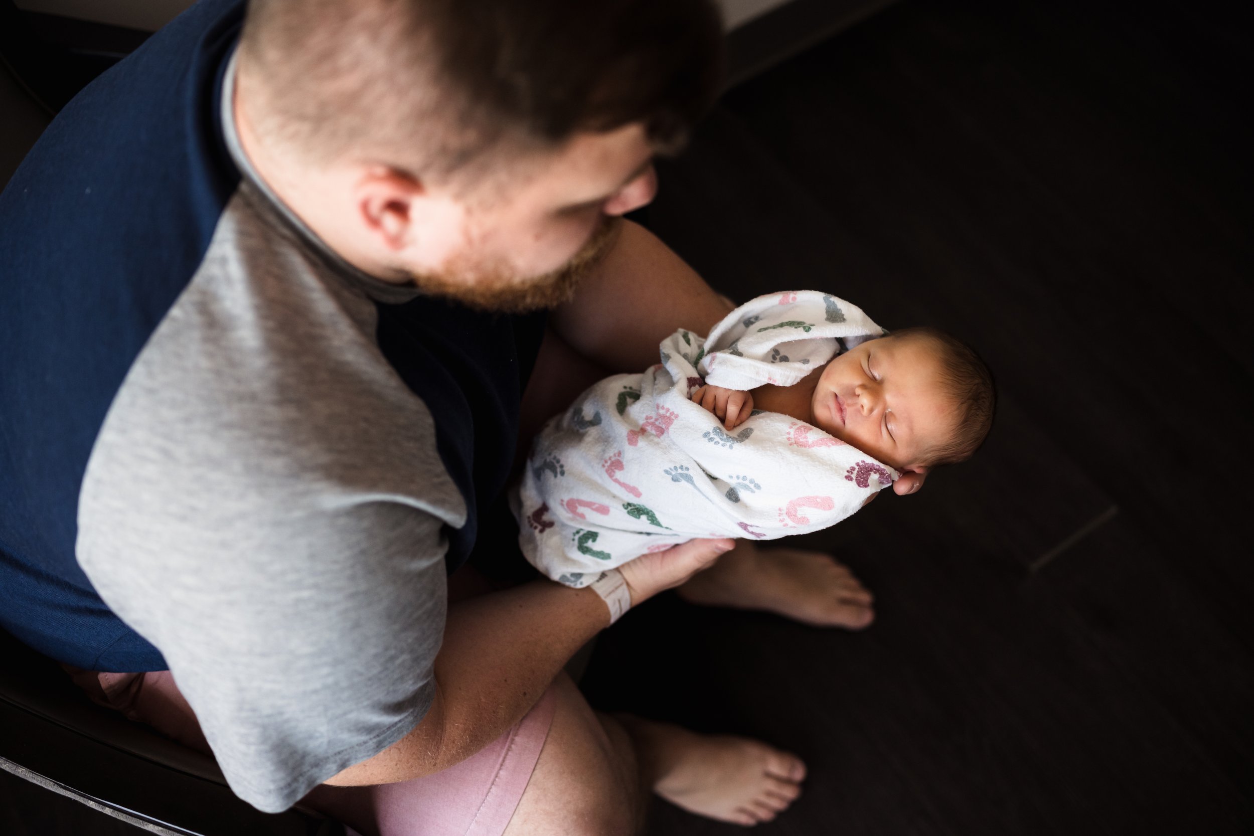 Dad holds newborn baby in hands wrapped in hospital swaddle Kathryn J birth Stories | Fresh 48 guide | Dallas birth photographer
