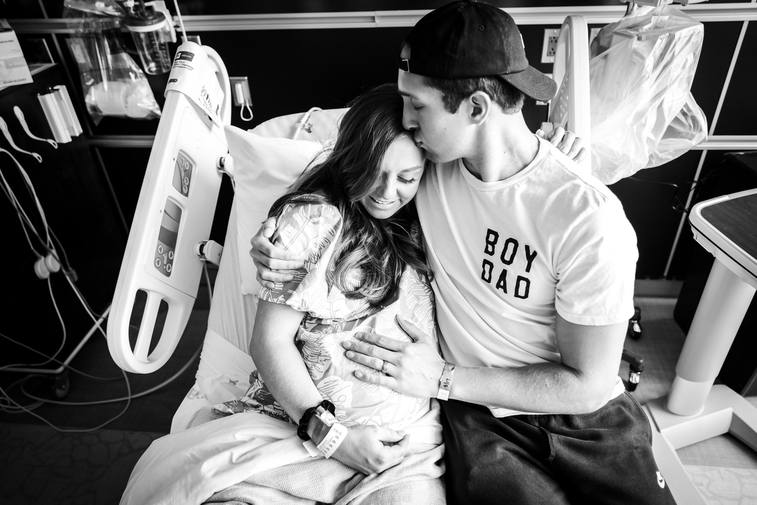 couple cuddles on hospital bed during induction of birth at hospital