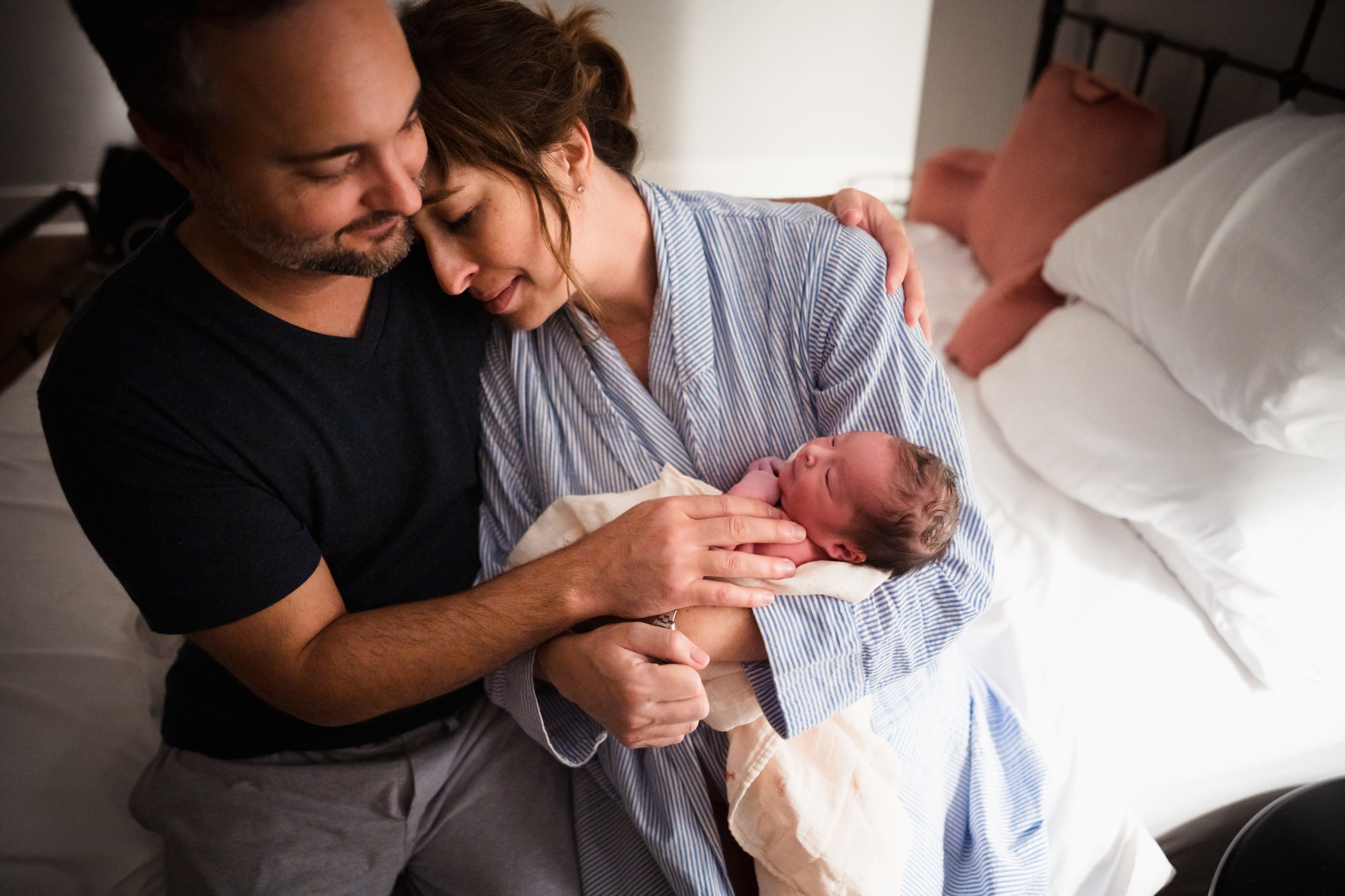 couple cuddles close with newborn in their arms after home birth in Fort Worth, TX