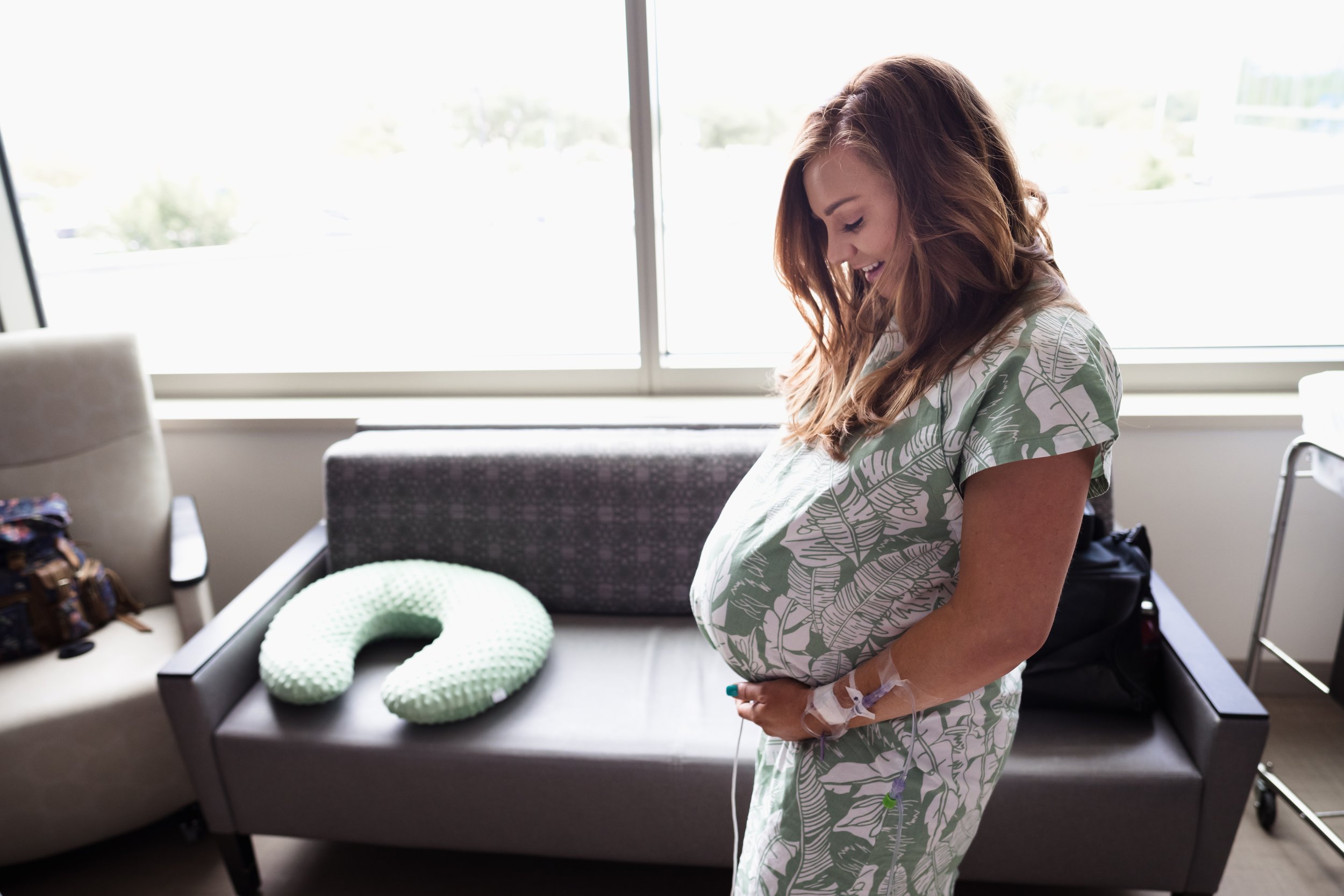 mother stands in front of window showing pregnant belly at Dallas hospital