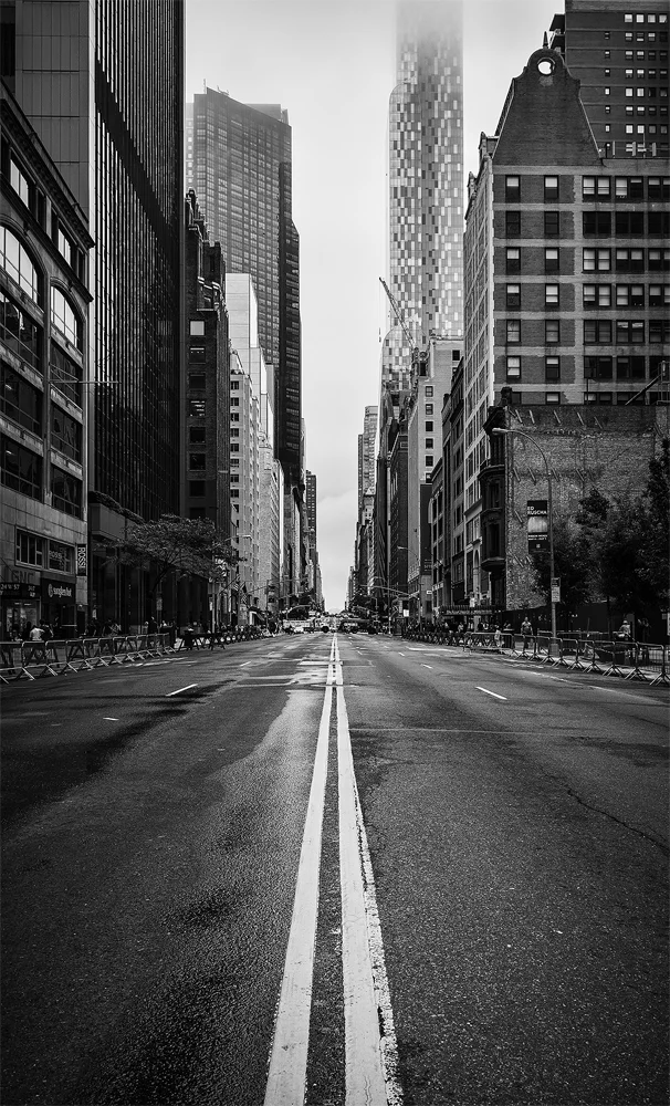 Being the most populous city in the USA, the main streets in New York are crowded pretty much 24/7. This time there was a parade of some kind going to take place on the 57th street, resulting in it being closed for motor vehicles. I rushed to take advantage of this chance to get a shot of the scene without cars. With the street empty, the road markings formed a clear leading line to the distance, where a couple of skyscrapers stood tall featuring also low-level clouds that highlighted their height further. Regarding technical aspects, the final image is a blended from three exposures. Post-processing, in turn, is done in Lightroom, Silver Efex Pro 2 and Photoshop.