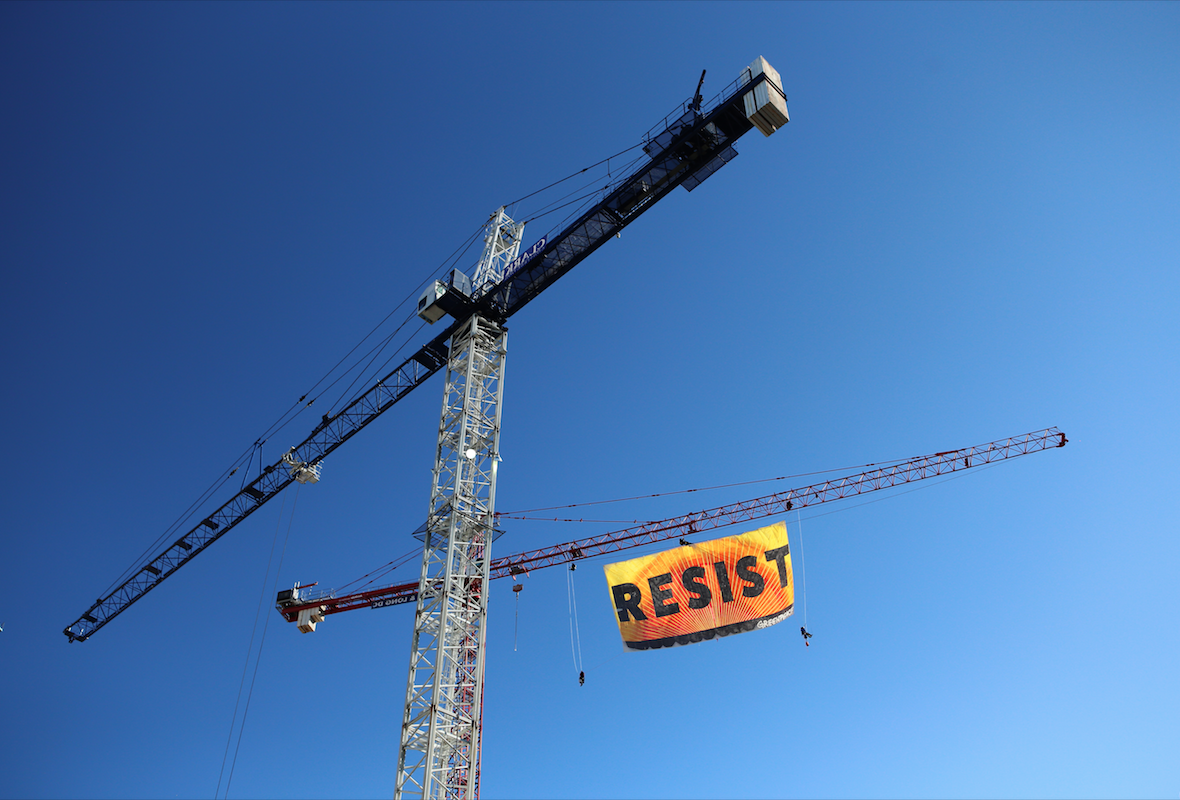  A banner deployed by Greenpeace hangs between two people from a crane just blocks from the White House. 