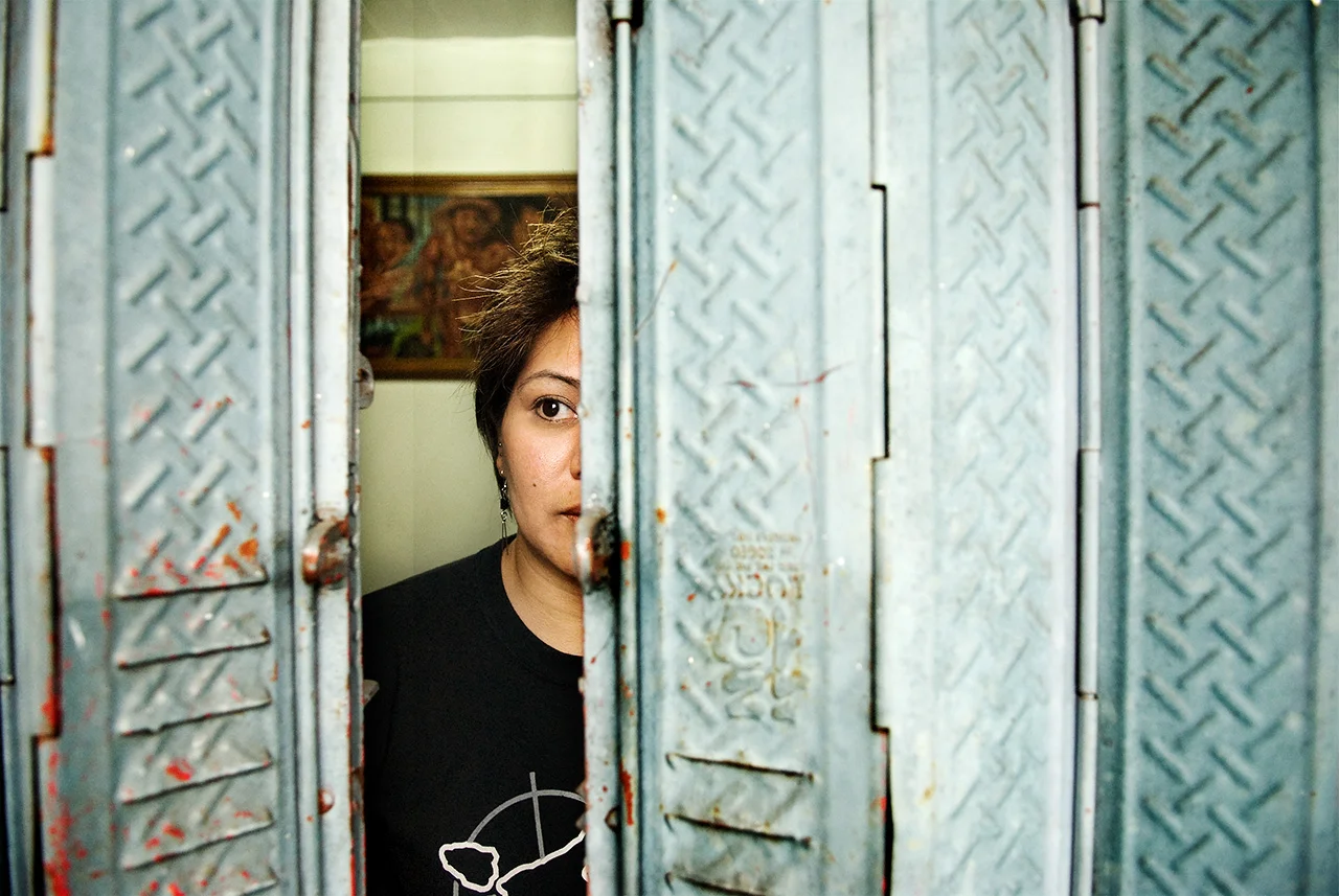Human Rights Lawyer Beverly Longid hides behind the blinds of a window.