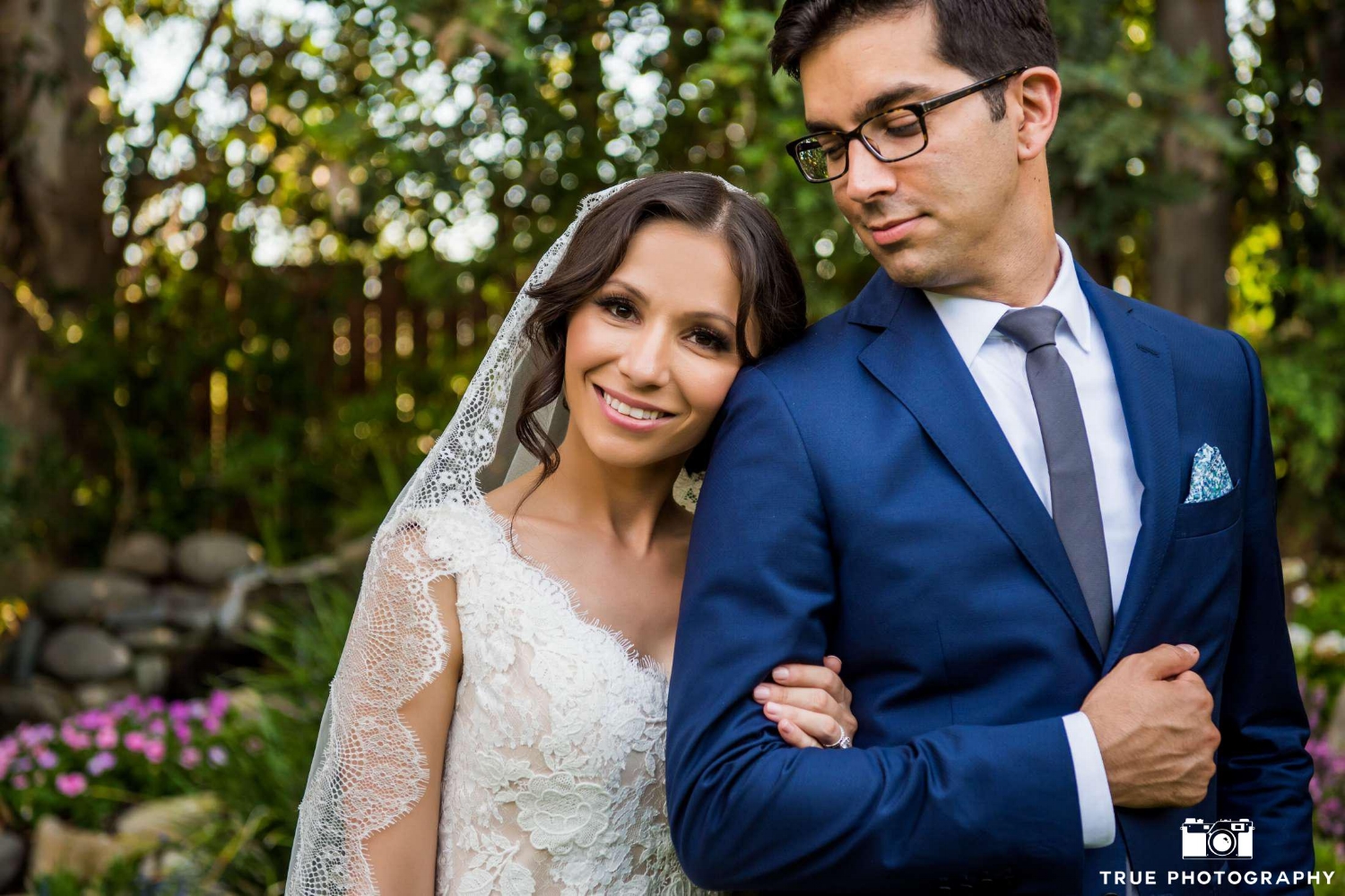 Petite Hispanic Bride in Lace Veil Posing in Wedding Photos with Husband. Bridal Hair and Makeup by Vanity Belle in Orange County (Costa Mesa) and San Diego (La Jolla) 