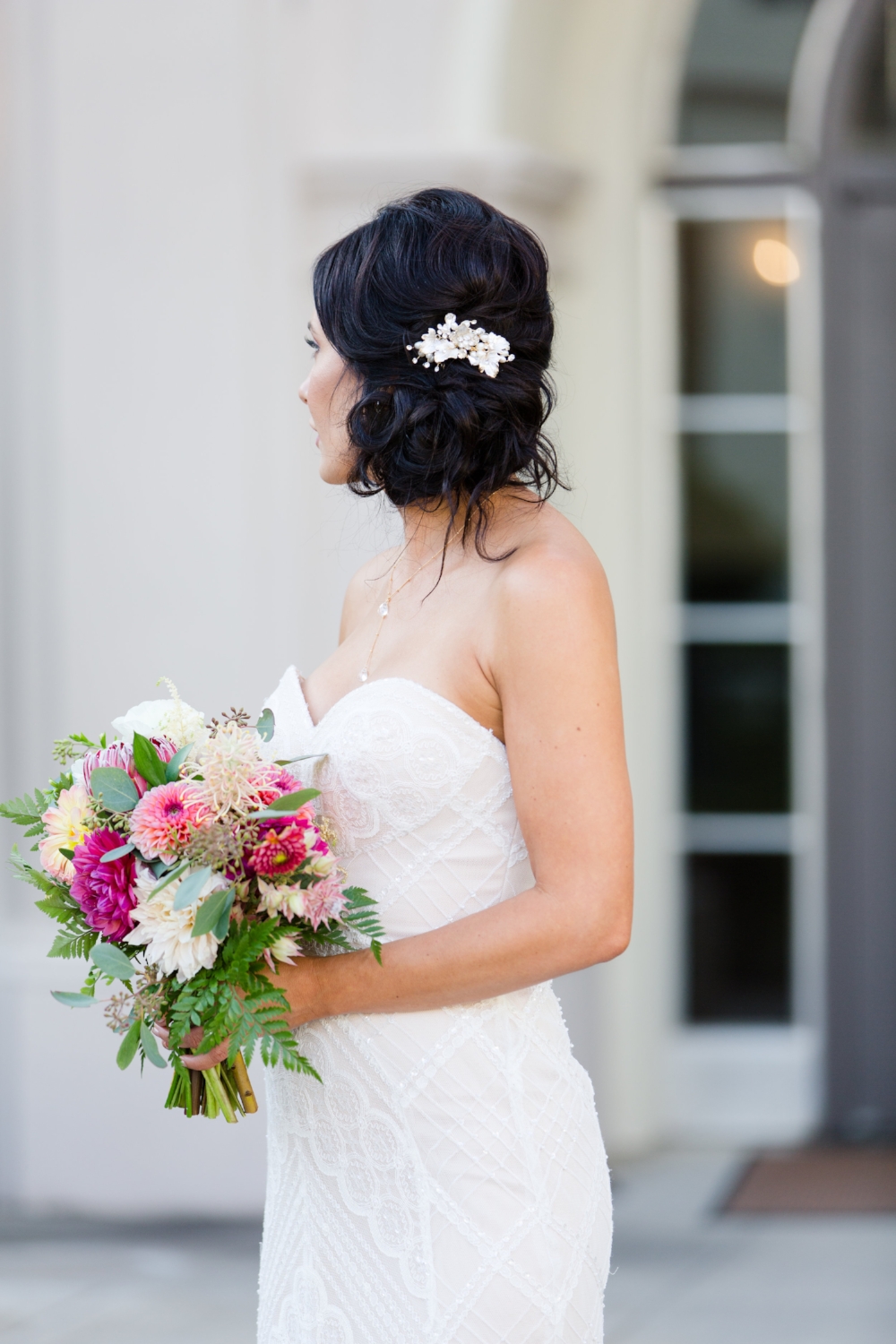  Brunette Bride with Updo and hair accessory holding bouquet outside in Wedding Photography. Bridal Hairstyles and Makeup by Vanity Belle in Orange County (Costa Mesa) and San Diego (La Jolla) 