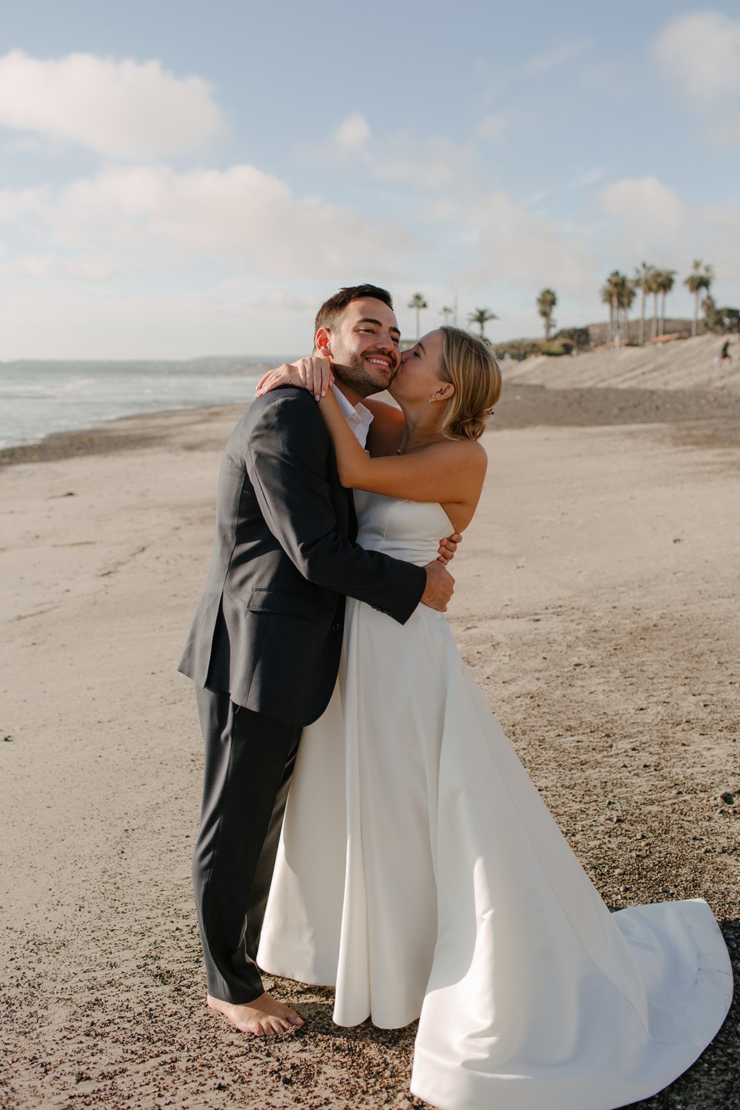 bride kissing groom on the beach