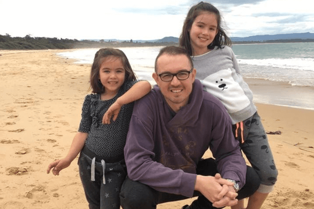 Andrew McGuire and his two daughters at the beach.