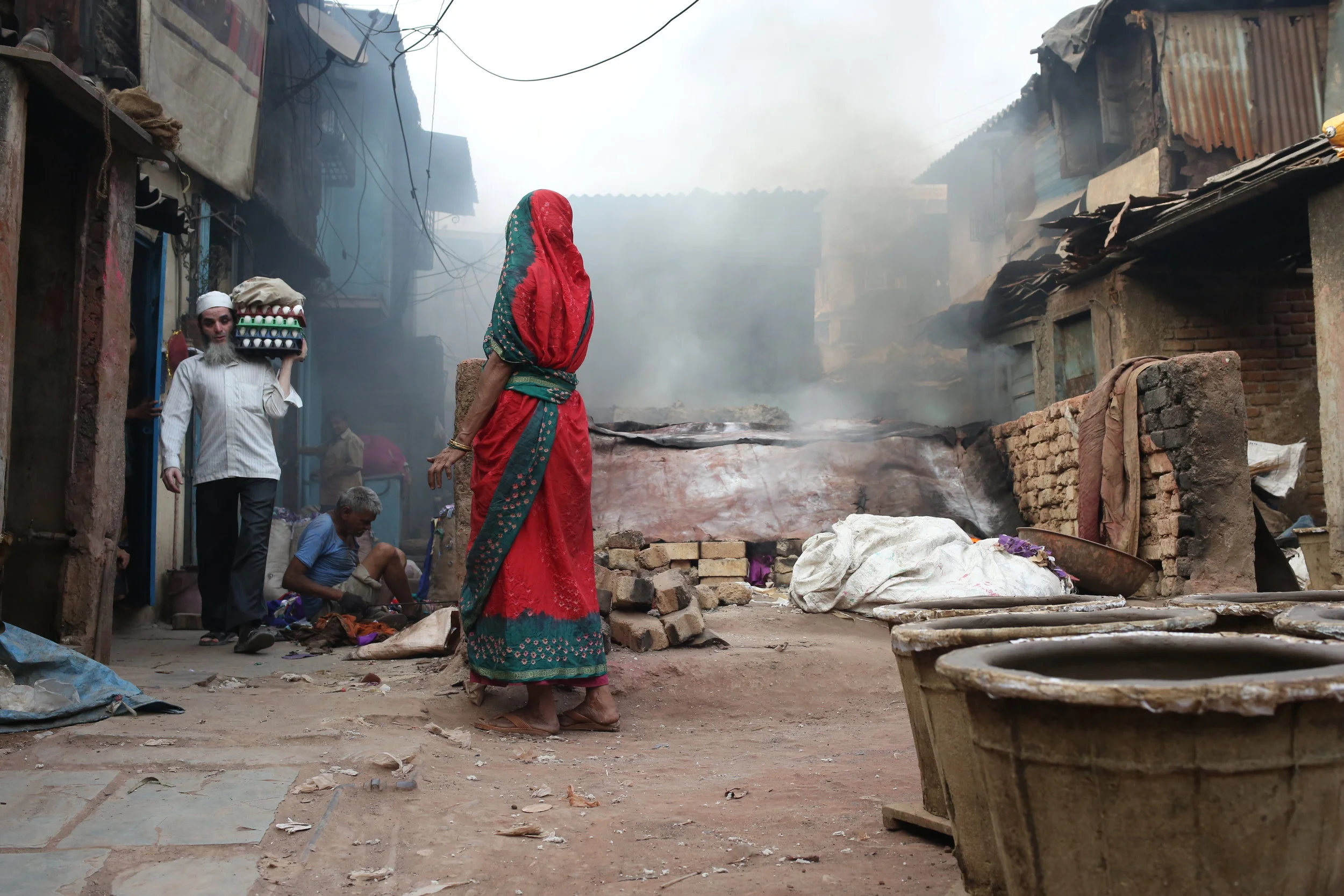  A Gujarat pot maker, watching over an open kiln.&nbsp; The fire is kept burning using fabric scraps from Dharavi's garment district. 