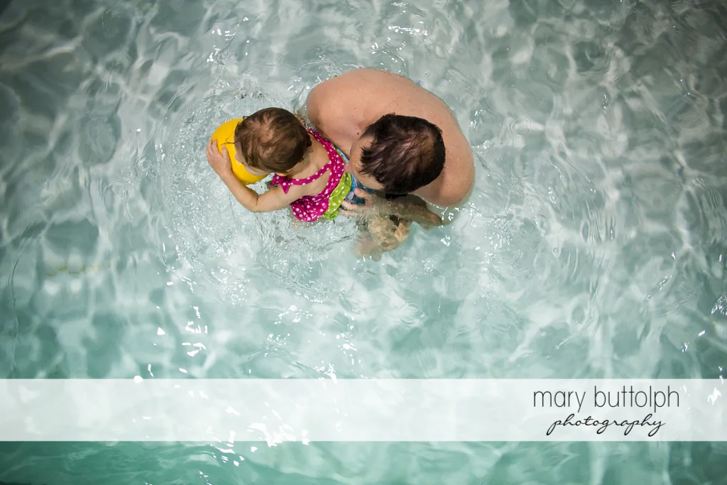 Overhead shot of girl and her father playing in the pool at Skaneateles
