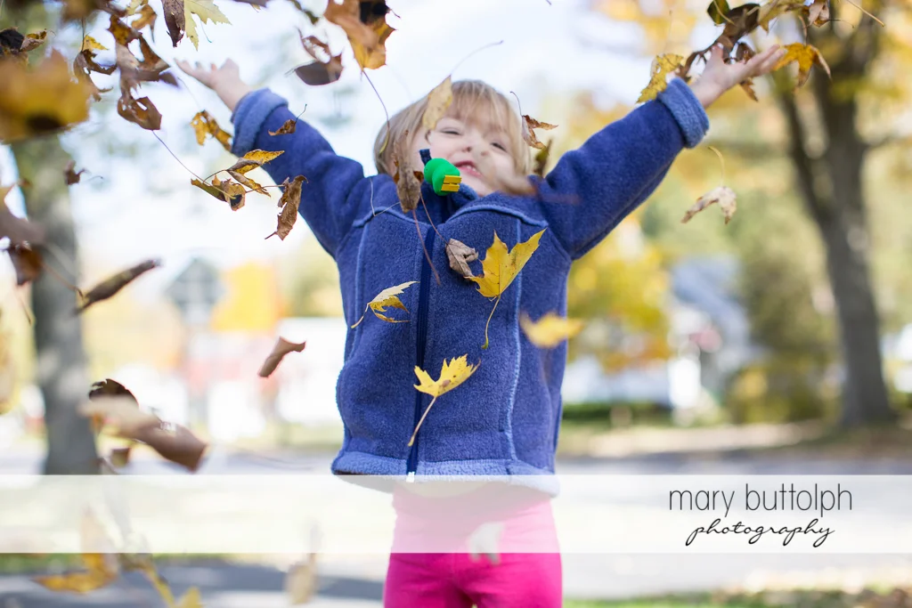 Girl playing with the leaves in the yard at Skaneateles
