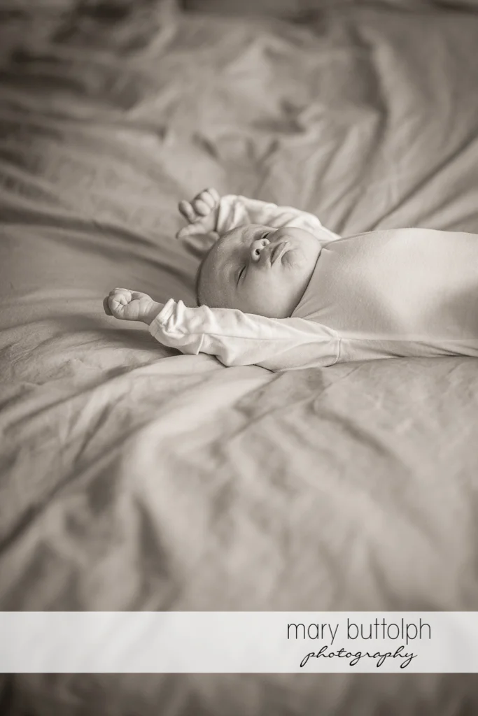Baby stretches in bed at Skaneateles Newborn Photography