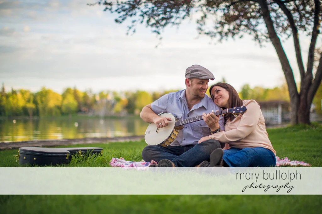 Man plays the banjo for his female companion near the lake at Skaneateles Engagement
