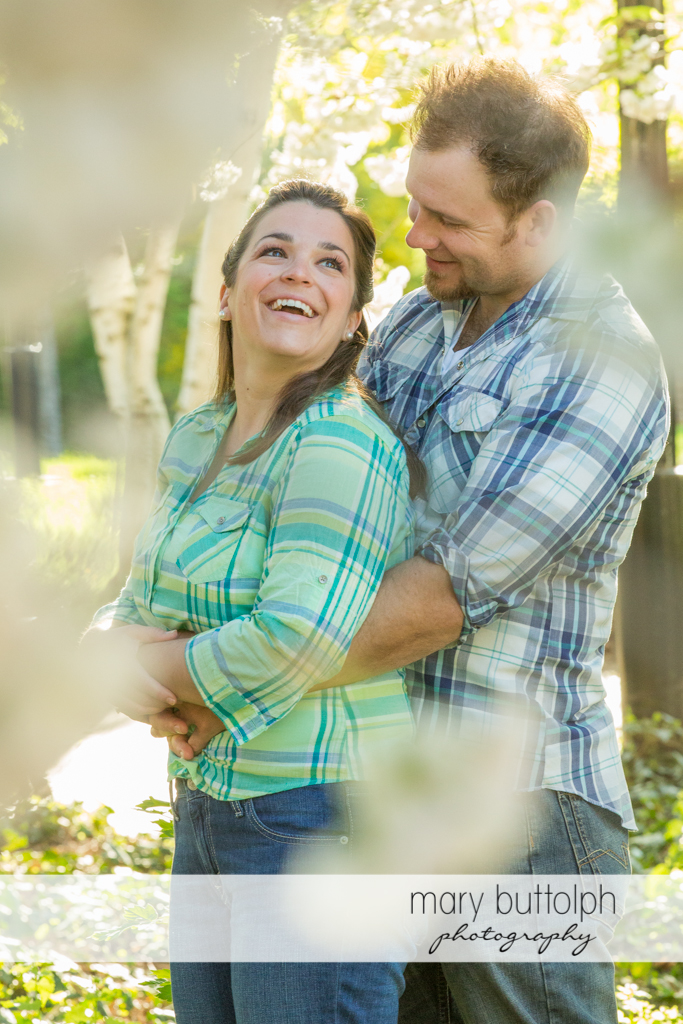Couple share a light moment in the garden at Skaneateles Engagement