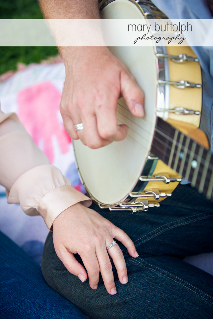 Close up of woman's engagement ring as her companion plays the banjo at Skaneateles Engagement