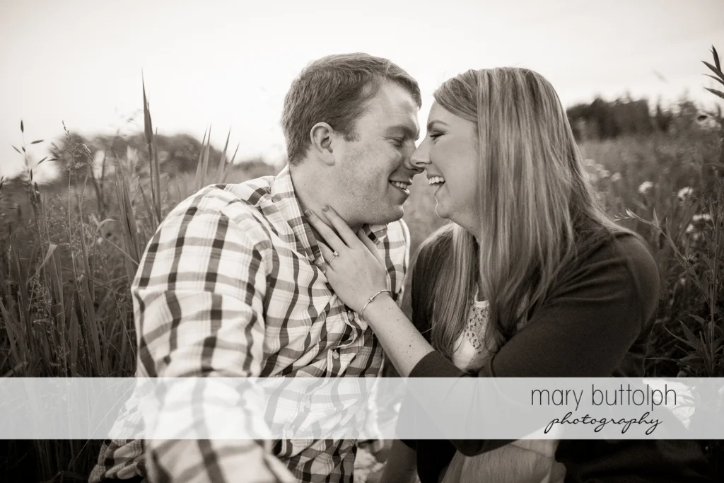 Couple share a laugh in the field at Skaneateles Engagement