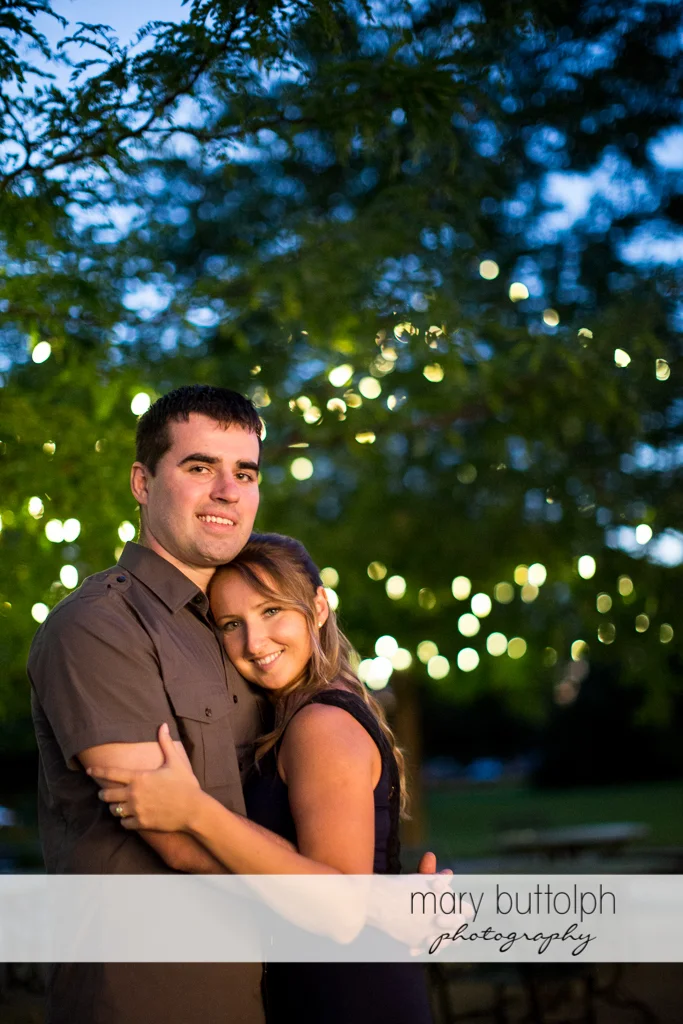 Couple stand under the tree lights at Emerson Park Engagement