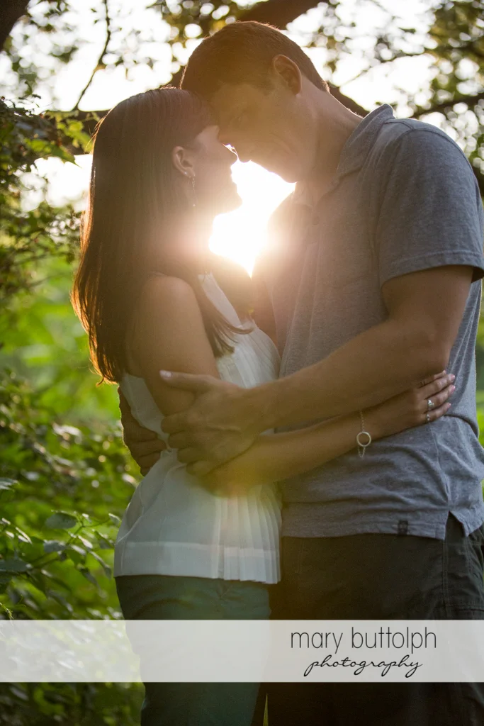 Couple embrace as the sun sets in the woods at Skaneateles Lodge at Welch Allyn Engagement