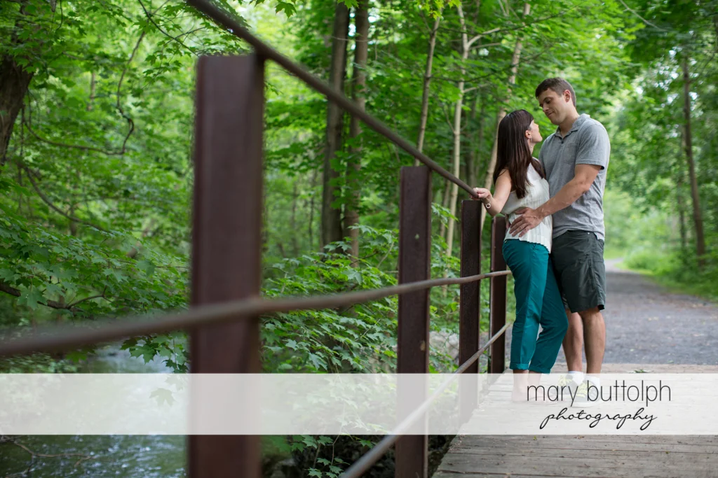 Couple pose near the steel bridge railing at Skaneateles Lodge at Welch Allyn Engagement