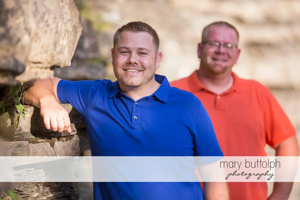 Same sex couple pose near a rock at Salmon River Falls Engagement