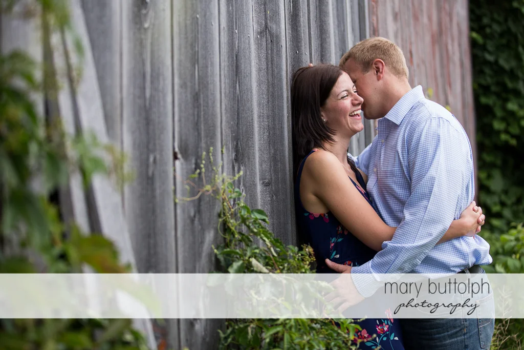 Couple have fun near a wooden structure at Skaneateles Farm Engagement