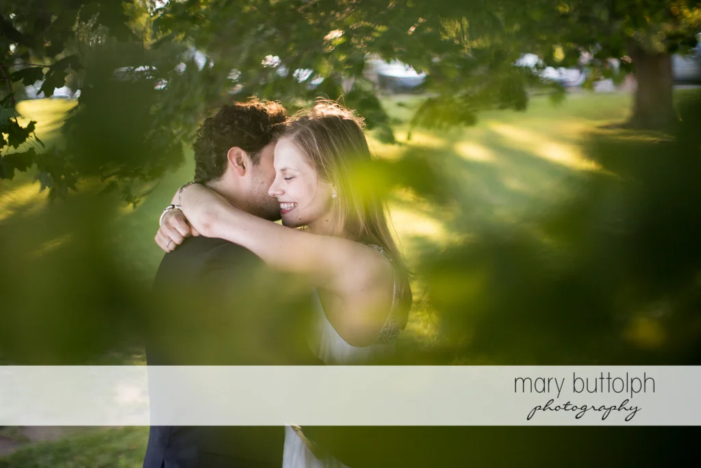 Couple embrace in the garden near the trees at Skaneateles Engagement