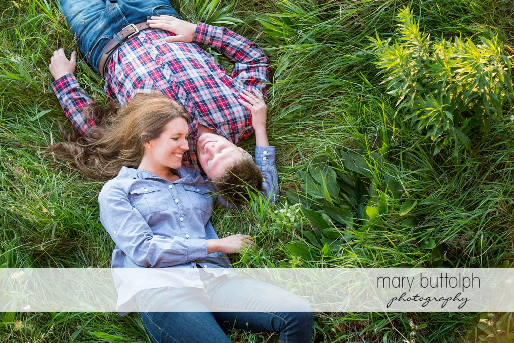 Couple lie on the grass in the field at Aurora Engagement