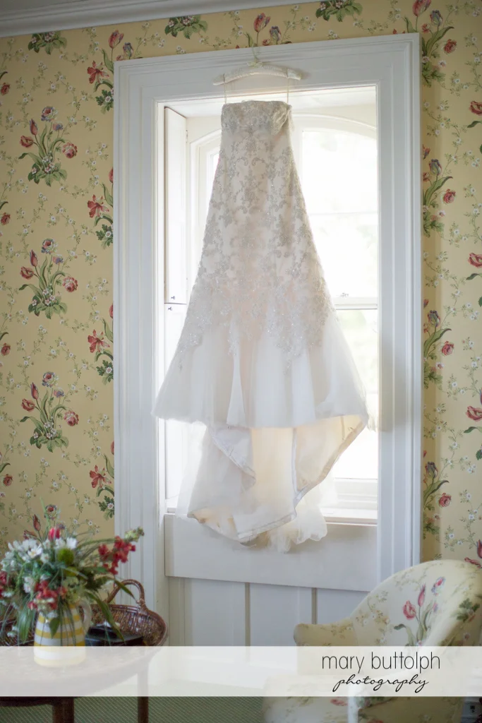 Bride's wedding dress hangs from the window at the Inns of Aurora Wedding