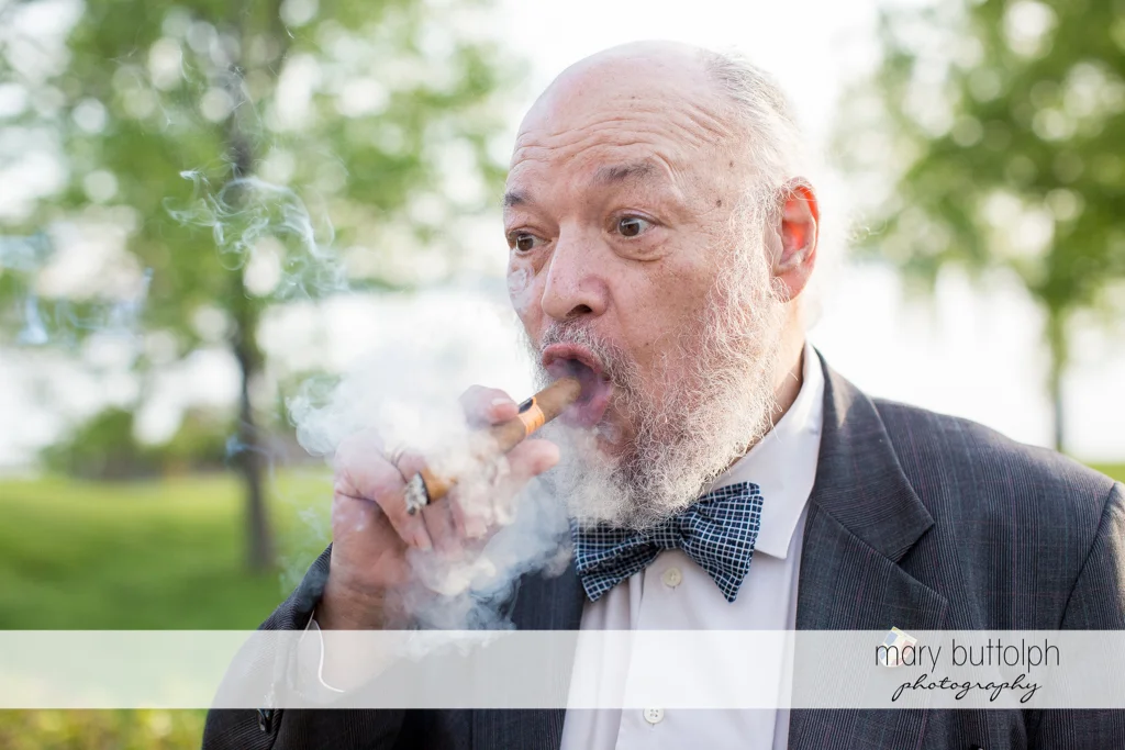 Bride's father smokes a cigar in the garden at the Inns of Aurora Wedding