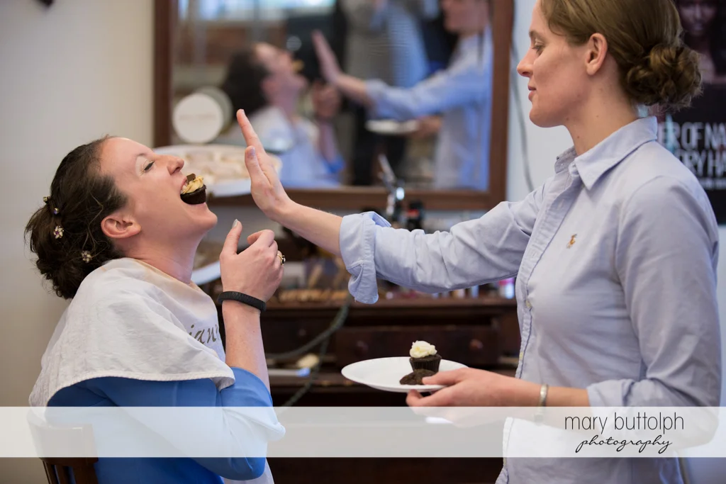Bride gets a mouthful of cupcake from a friend at the Inns of Aurora Wedding