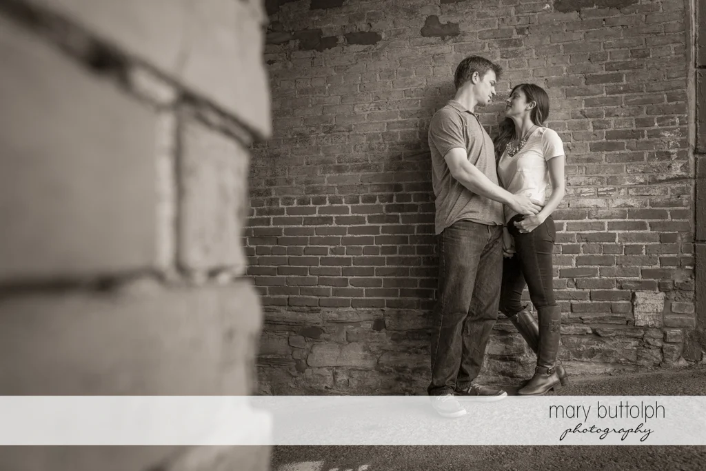 Couple pose in front of a brick wall at Skaneateles Engagement