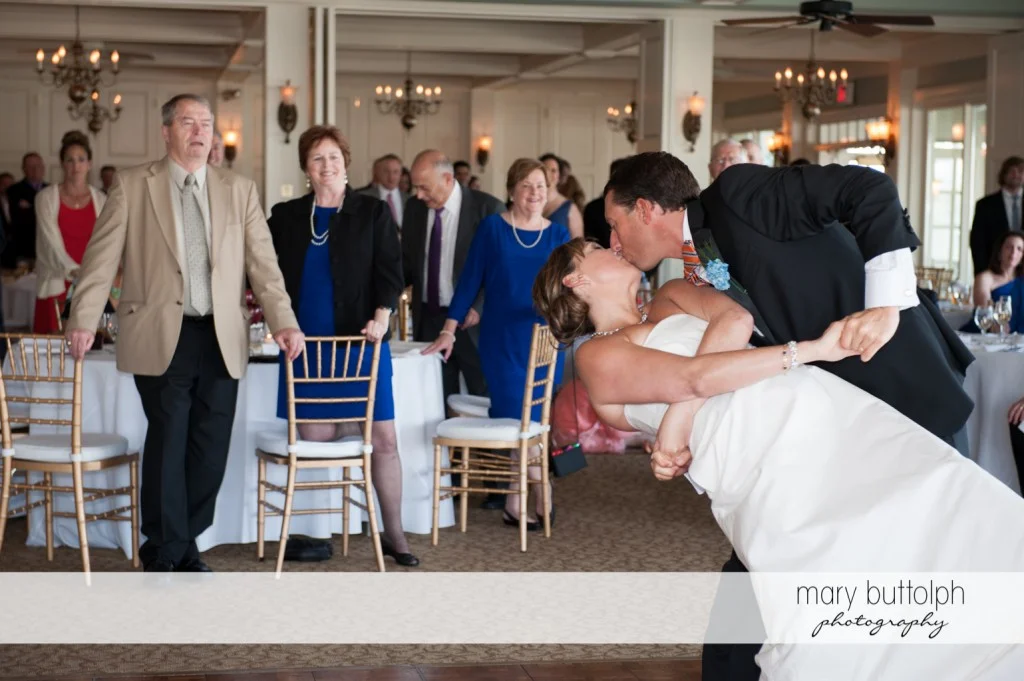 Couple kiss as guests look on at Skaneateles Country Club Wedding