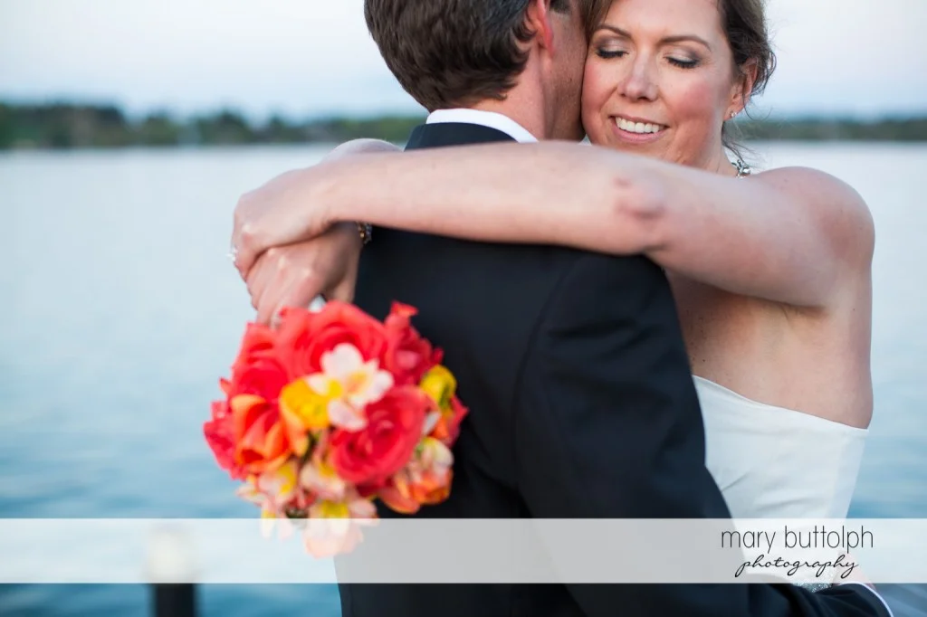 Couple embrace by the lake at Skaneateles Country Club Wedding
