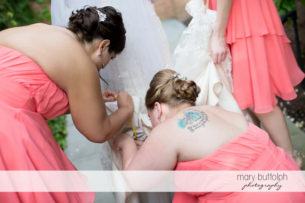 Bridesmaids busy fixing the bride's wedding dress at the Inns of Aurora Wedding