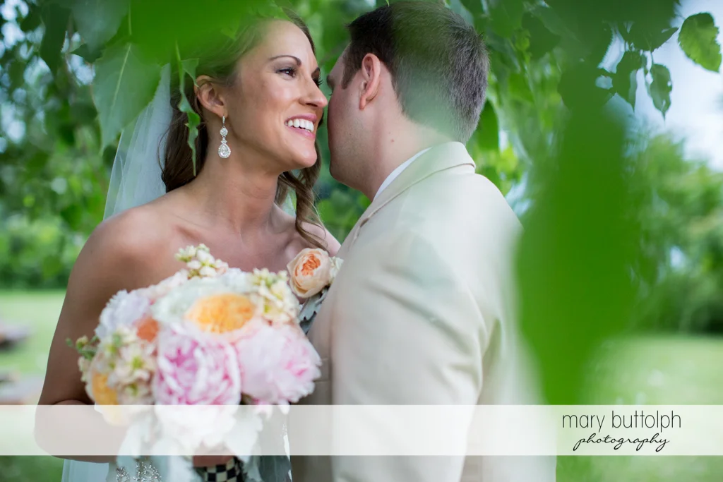 Groom whispers to the bride in the garden at the Inns of Aurora Wedding