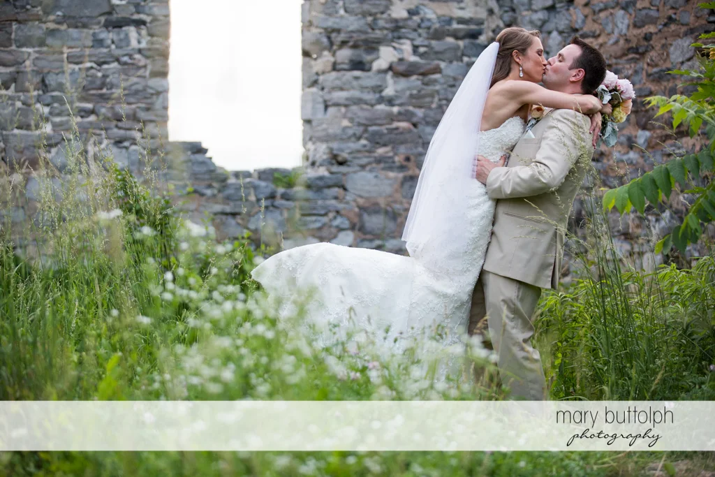 Couple kiss by the ruins at the Inns of Aurora Wedding