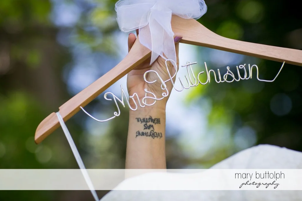 Tattooed bride shows her personalized hanger at Emerson Park Pavilion Wedding