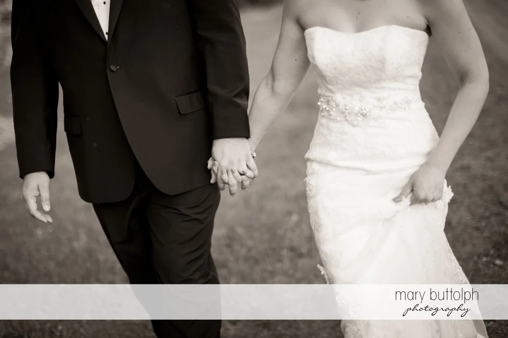 Medium shot of the couple holding hands while strolling in the garden at Emerson Park Pavilion Wedding