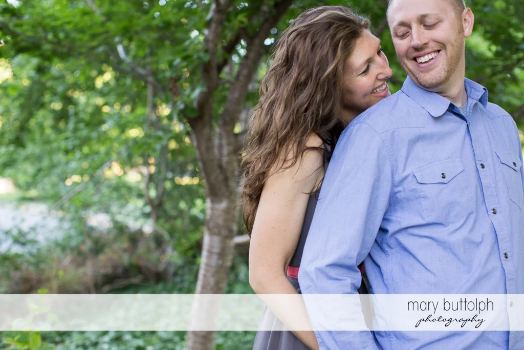 Couple smile near the trees in the garden at Franklin Square Engagement