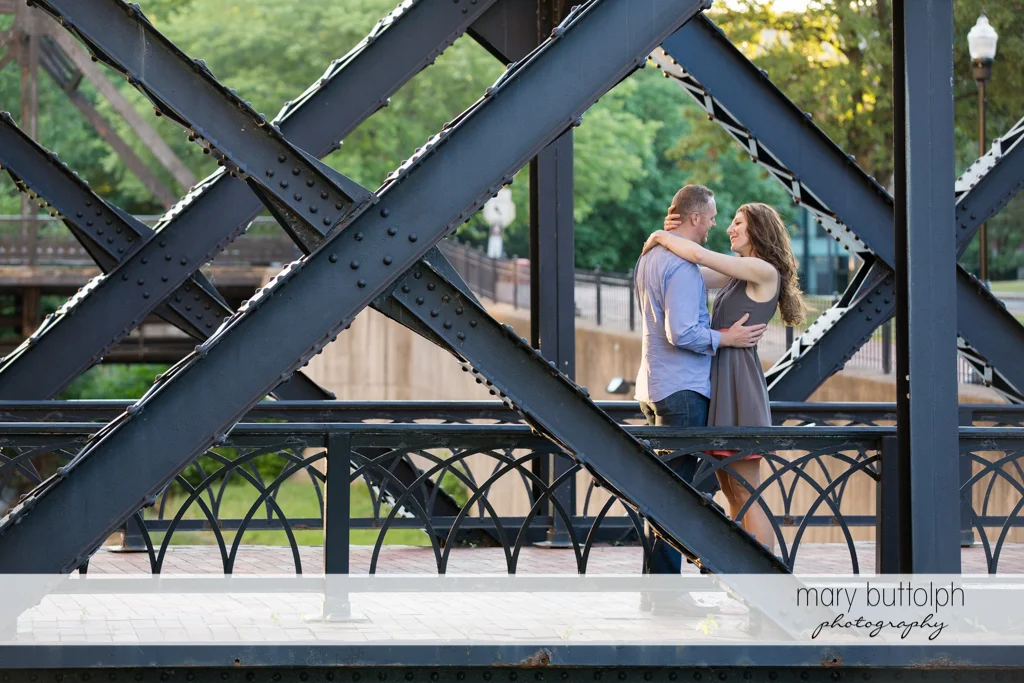 Couple embrace in the middle of a steel bridge at Franklin Square Engagement